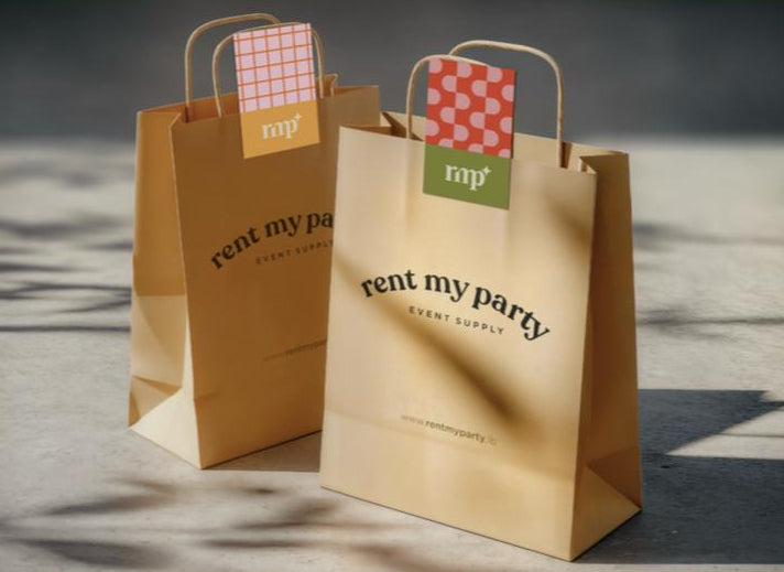 Two brown paper bags with 'rent my party' branding on a wooden surface.