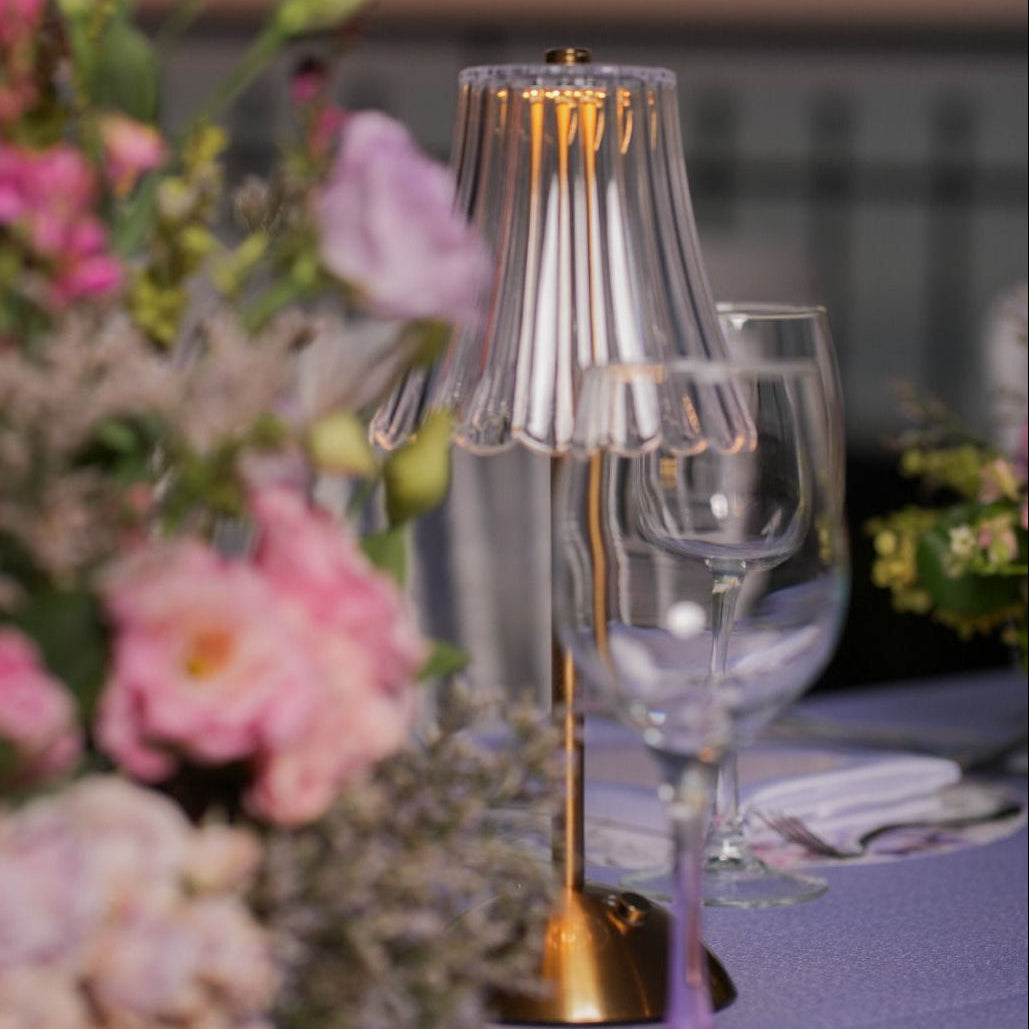 Decorative table setting with flowers and glassware against a sunset sky.