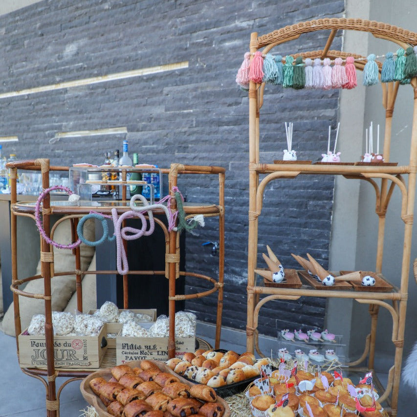 Bakery display with pastries on a hay-covered table against a stone wall.