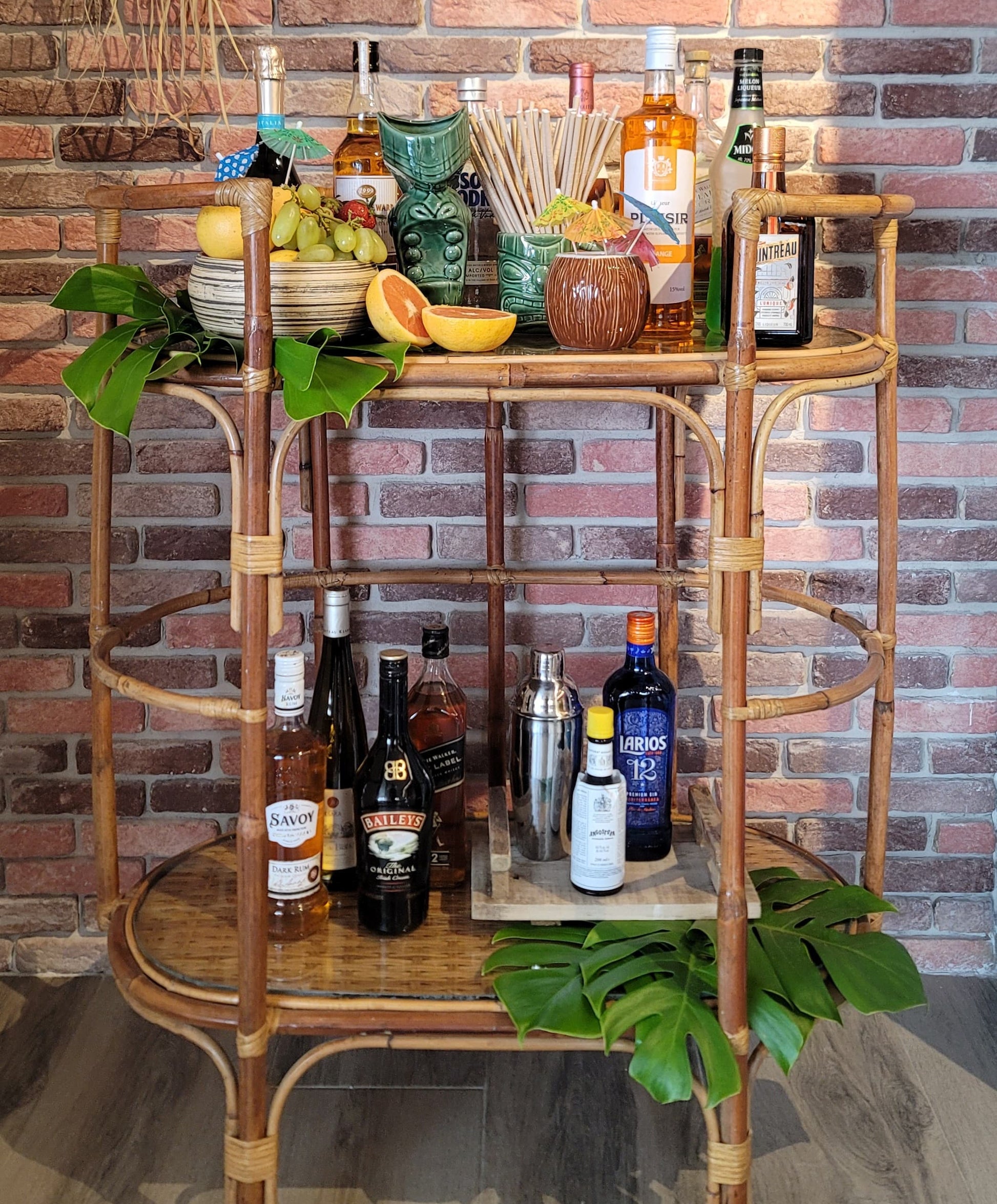 Bar cart with various bottles and glasses against a brick wall