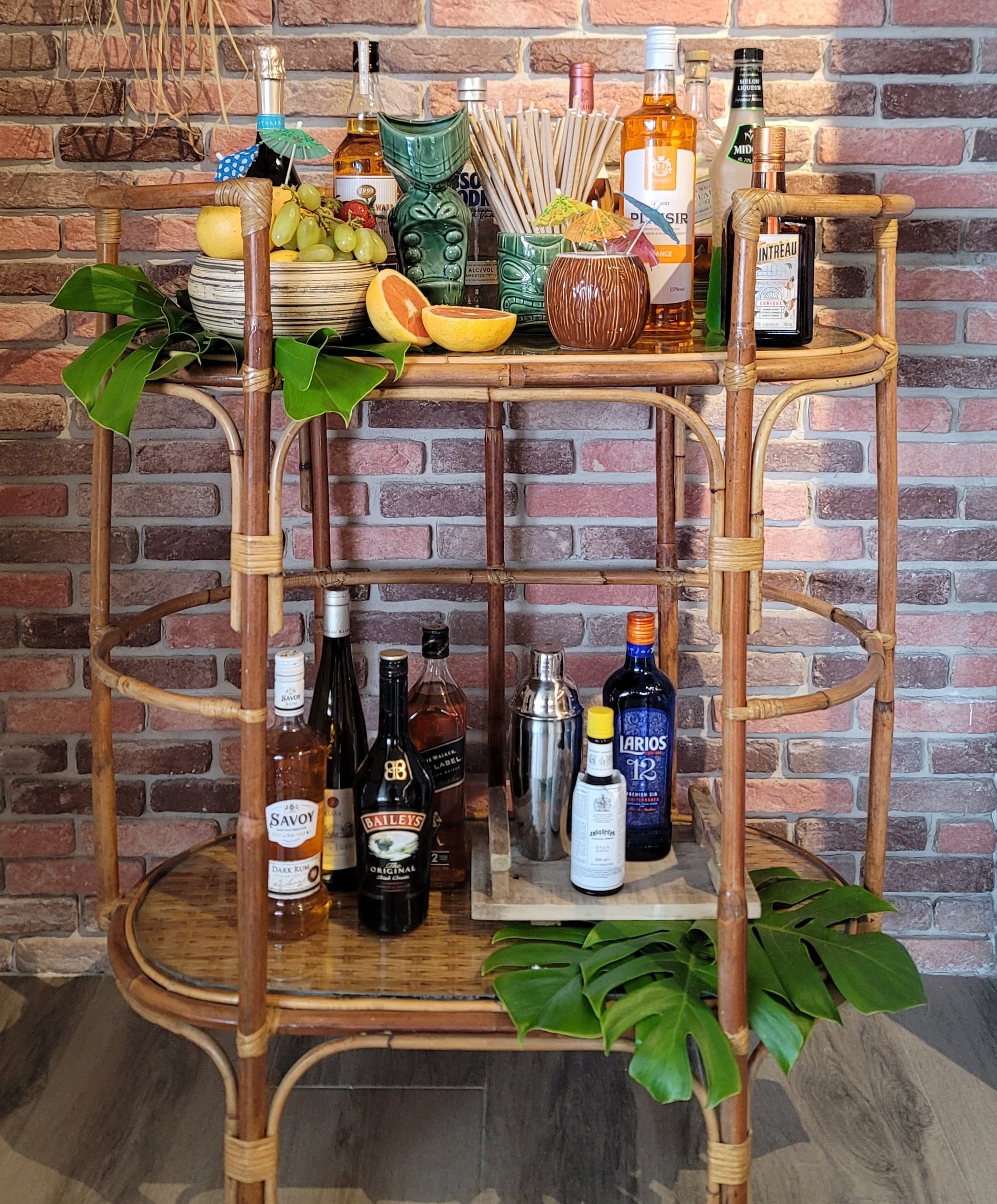 Bar cart with various bottles and glasses against a brick wall