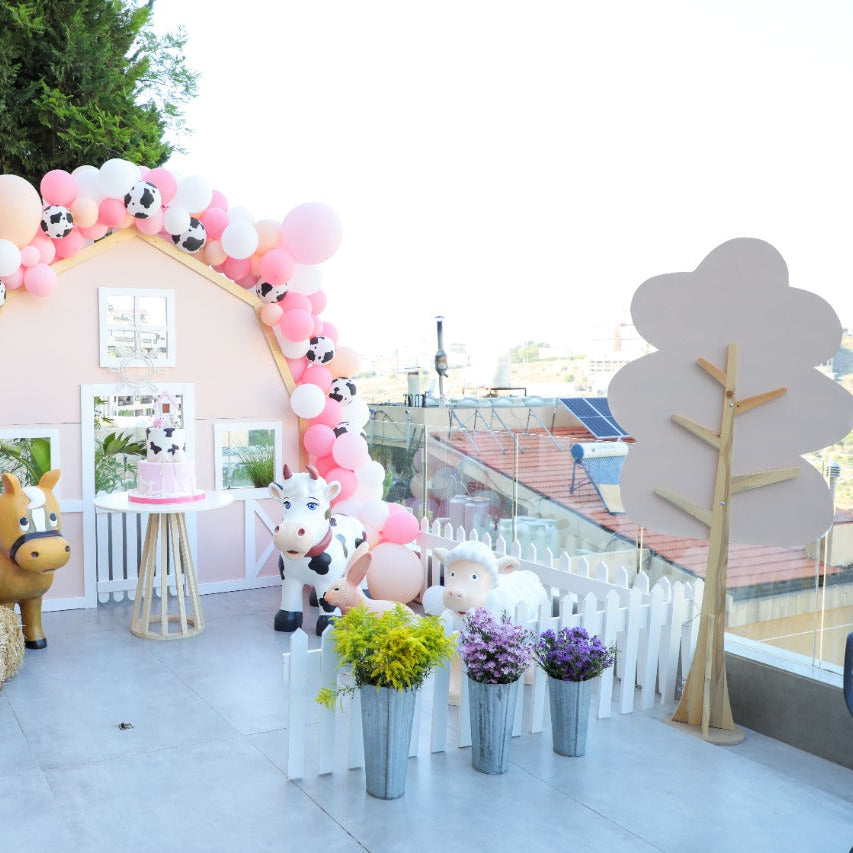 Decorative arch with balloons and cartoon character cutouts at an outdoor event.