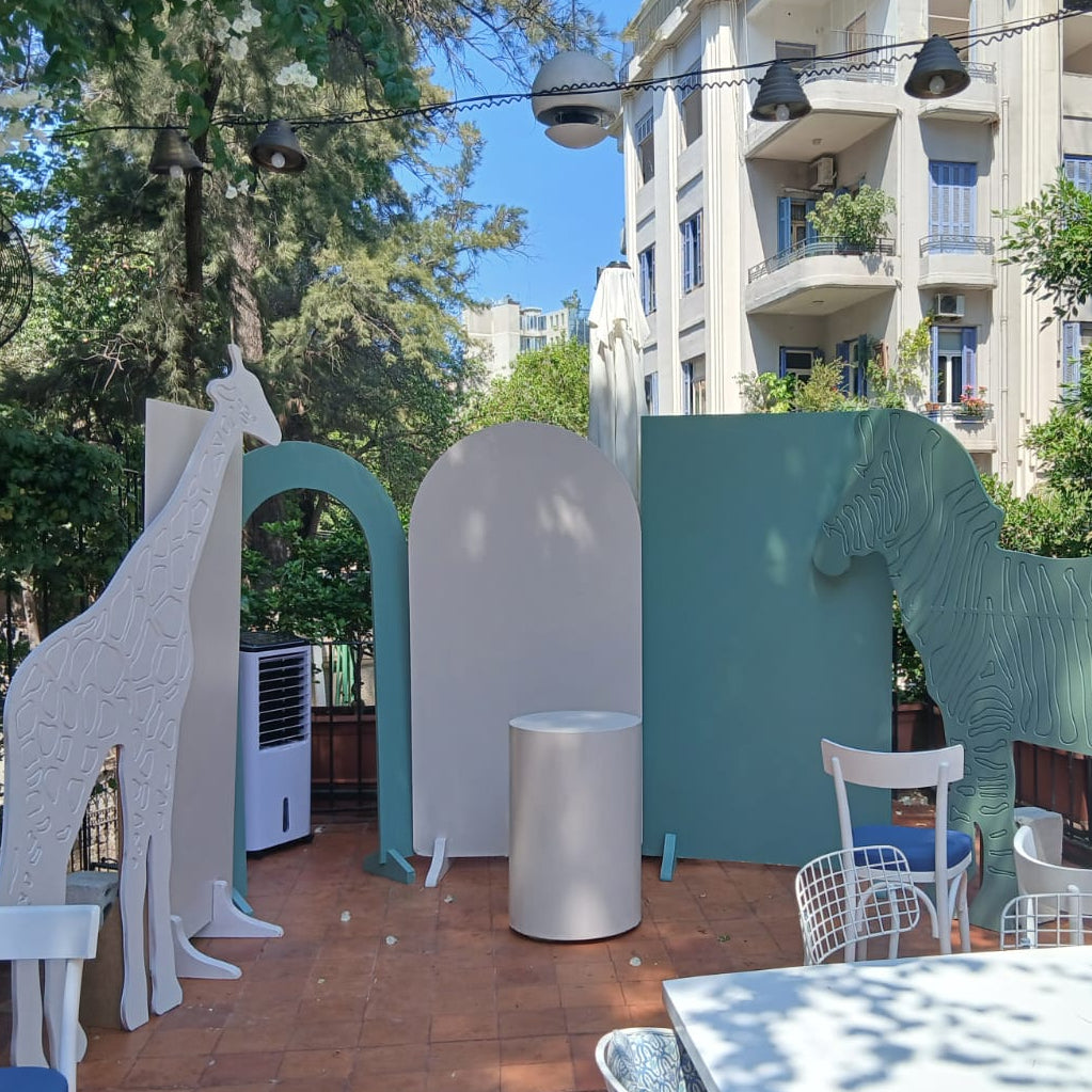 Outdoor setting with large animal sculptures and chairs under a tree