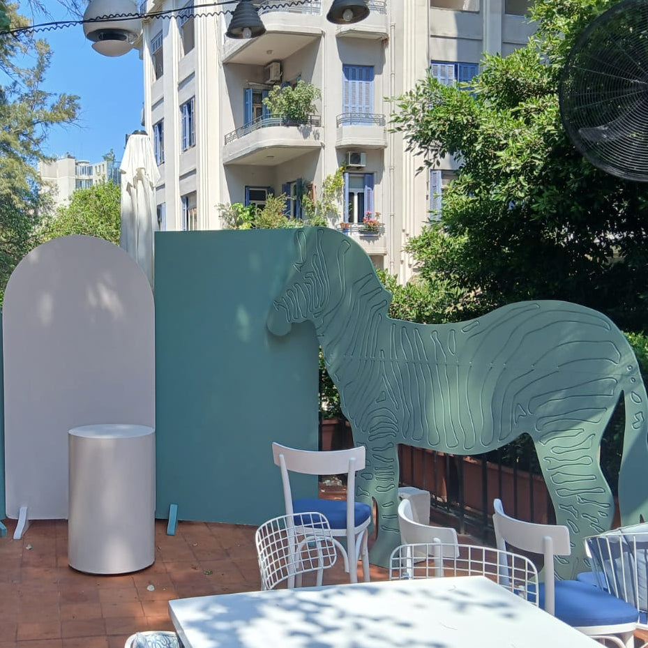 Outdoor setting with large animal sculptures and chairs under a tree