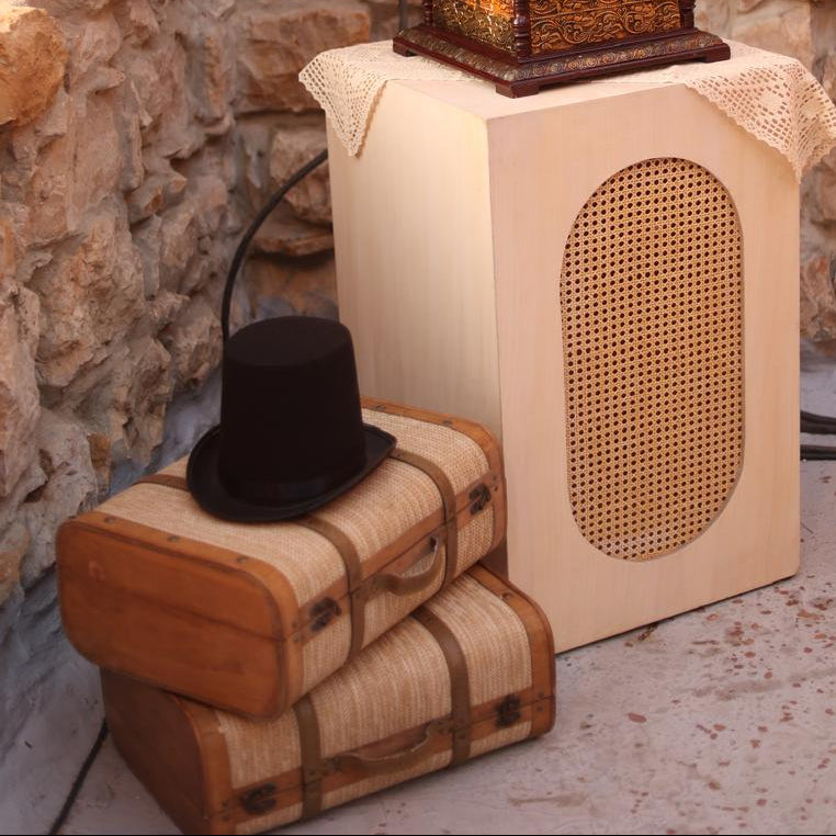 Vintage-style gramophone on a wooden stand against a stone wall.