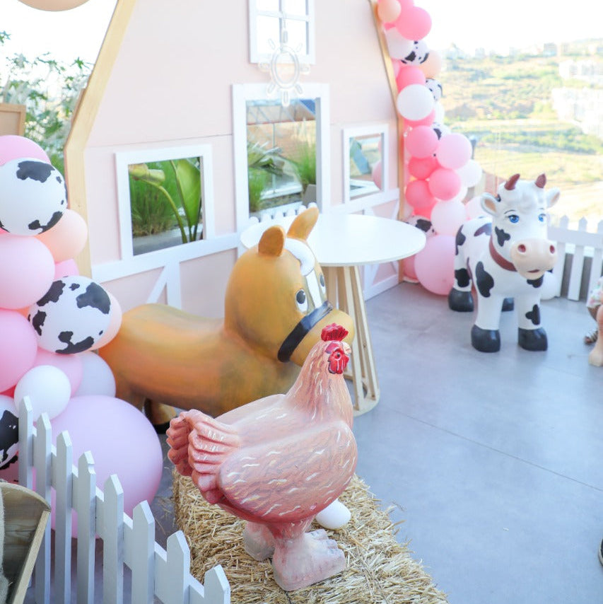 Decorative arch with balloons and farm animal-themed props on a rooftop.