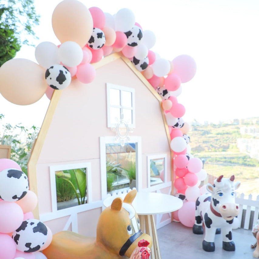 Decorative arch with balloons and farm animal-themed props on a rooftop.