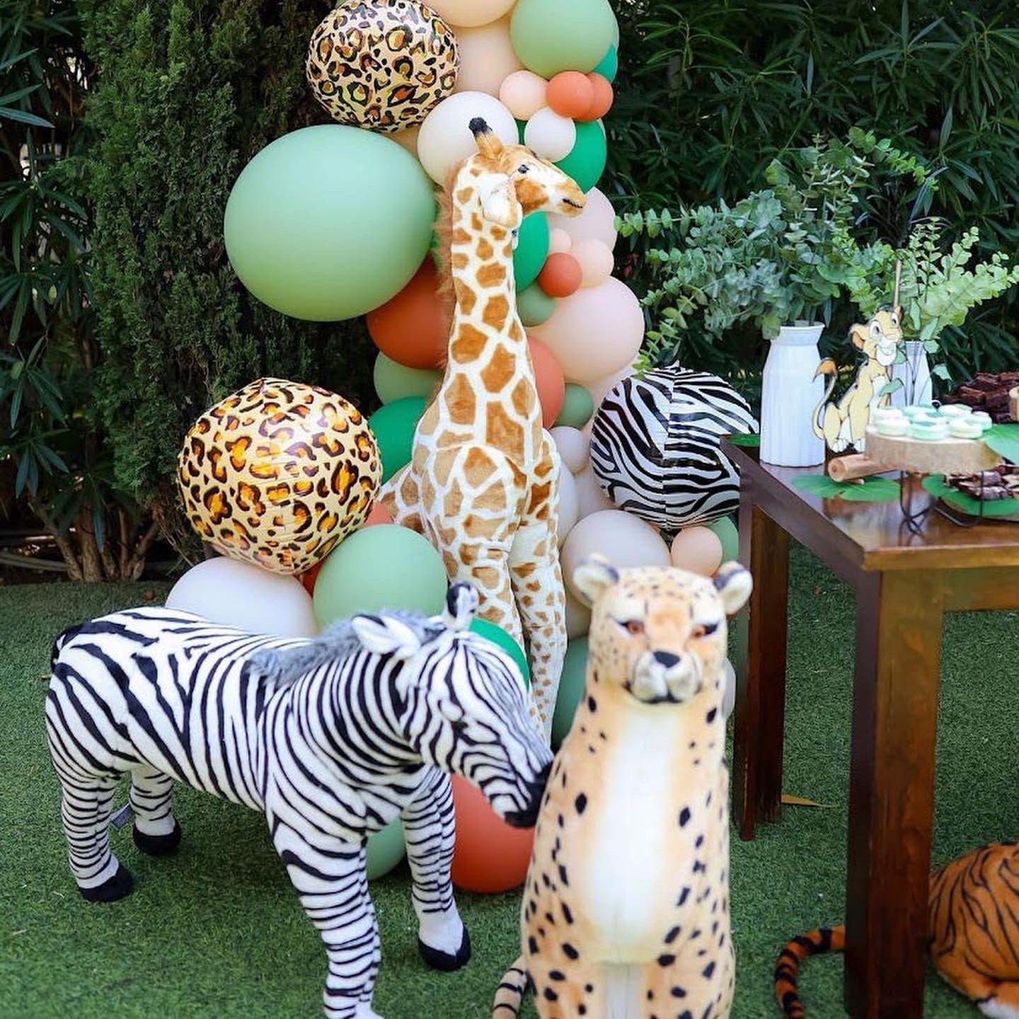 Decorative arch with balloons and animal-themed decorations in an outdoor setting