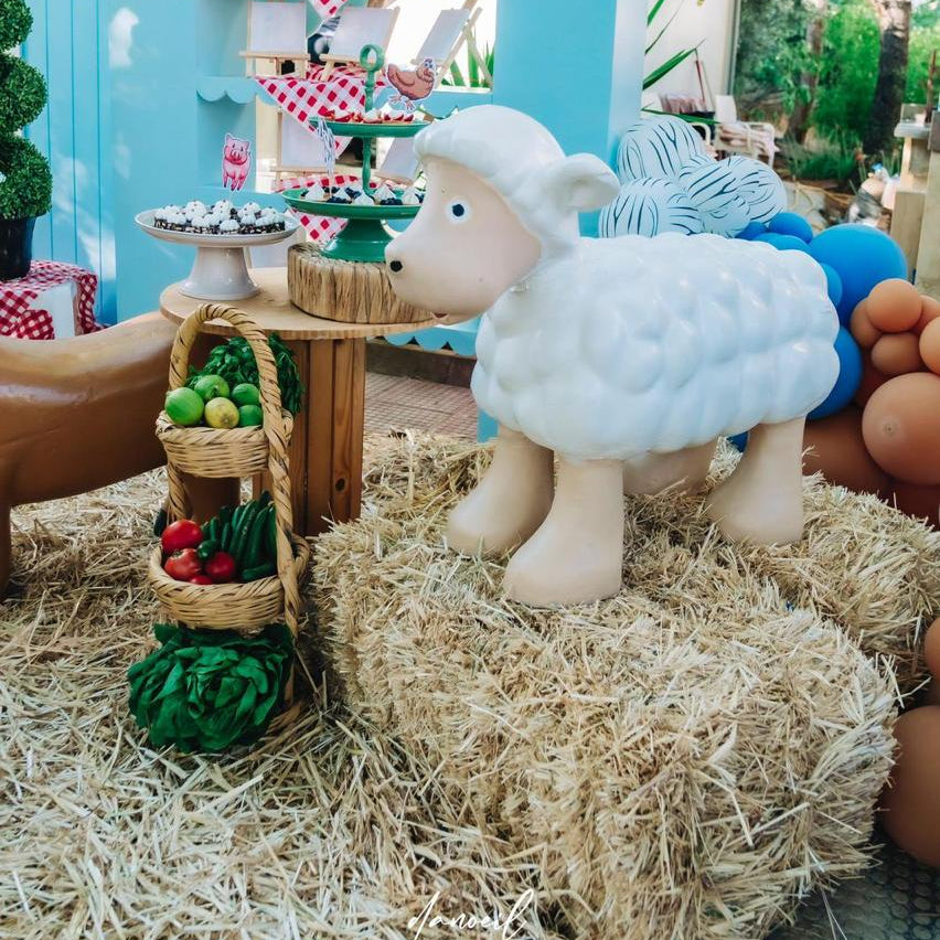 Sheep decoration on hay with a colorful arch and balloons in the background