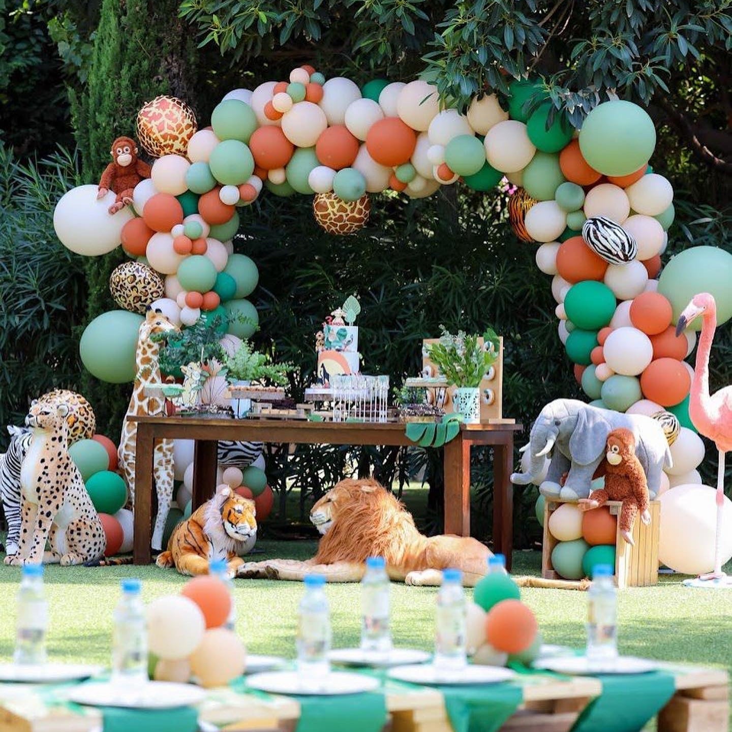 Jungle-themed birthday party with balloon arch, animal decorations, and table setup outdoors.