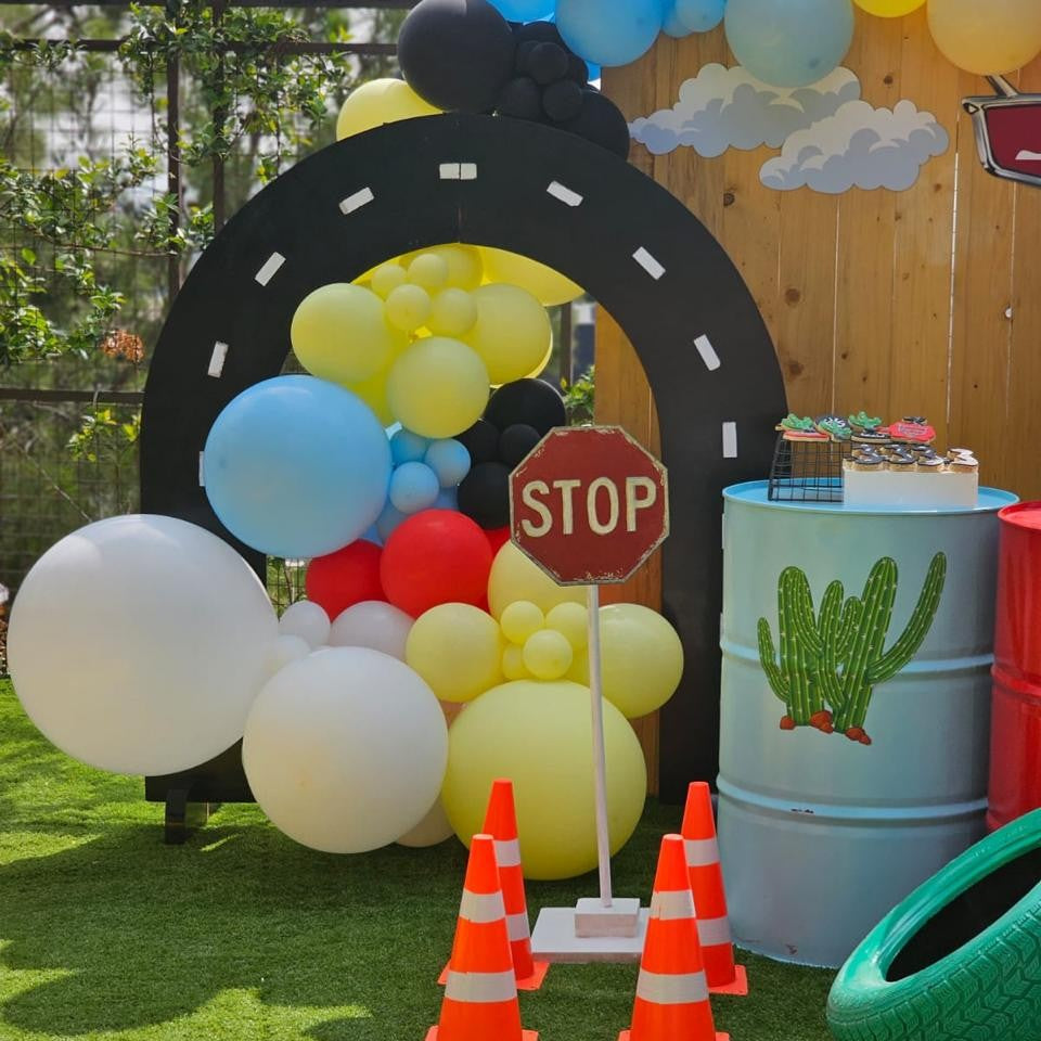 Decorative setup with balloons, a stop sign, and traffic cones on a grassy area.
Boys birthdays