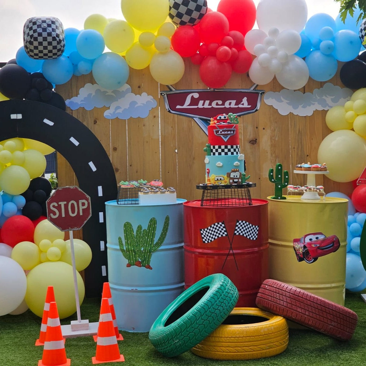 Children's birthday party setup with balloons, cake, and decorations themed around a car race.
