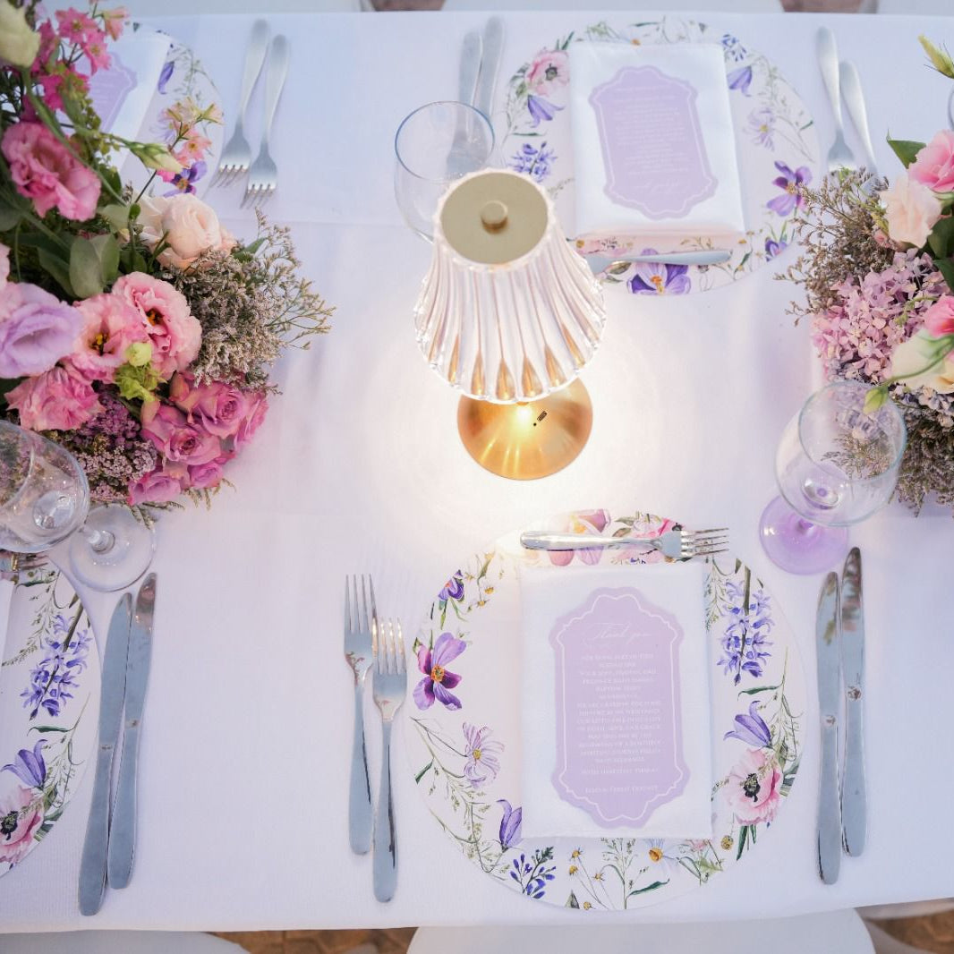 Elegant table setting with floral centerpieces, plates, and cutlery on a white tablecloth.