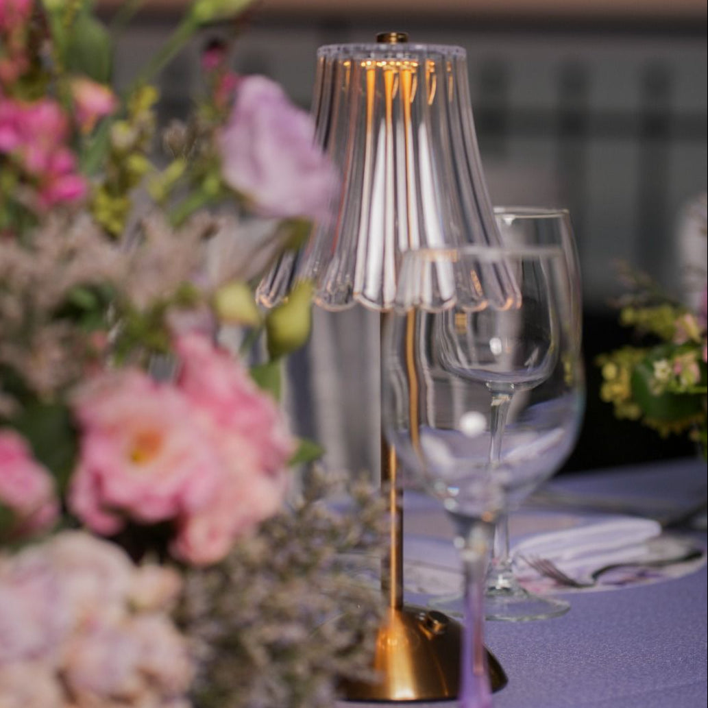 Decorative table setting with flowers and glassware against a sunset sky.