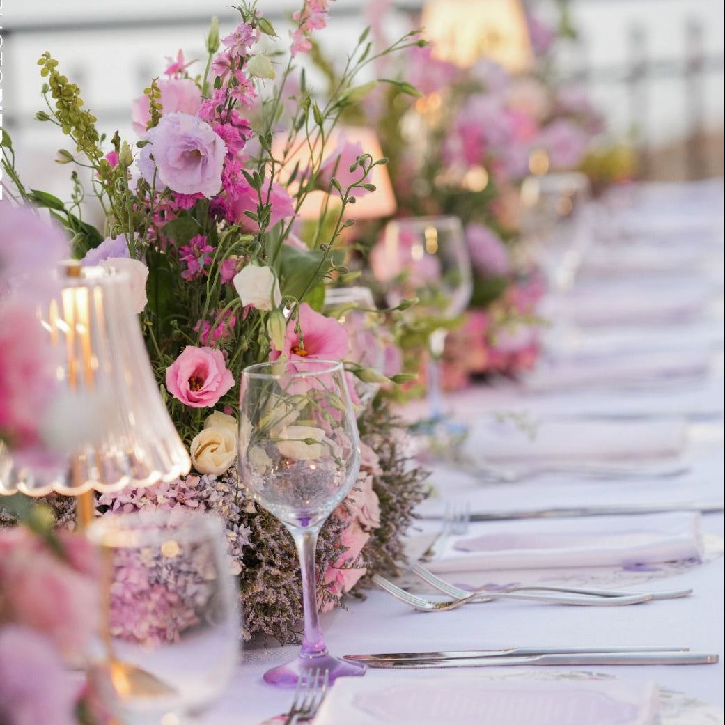 Elegant outdoor dining table setting with pink flowers and candles.