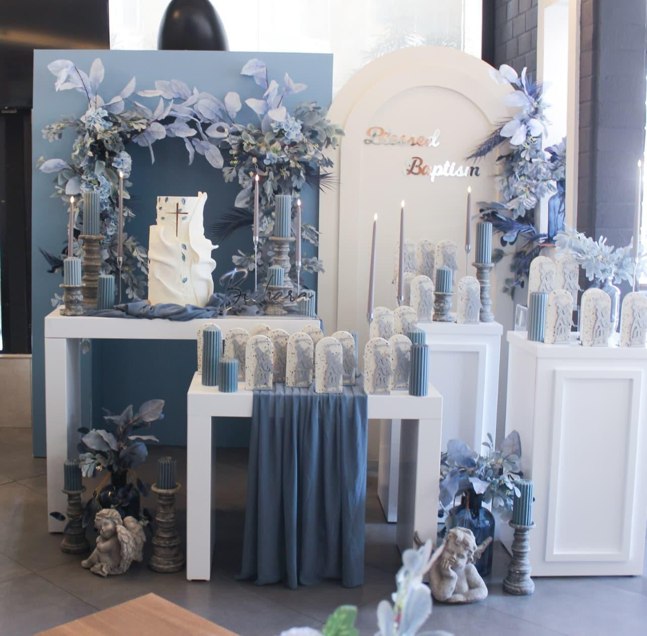 Decorative setup with candles, flowers, and decorative items on tables for baptism