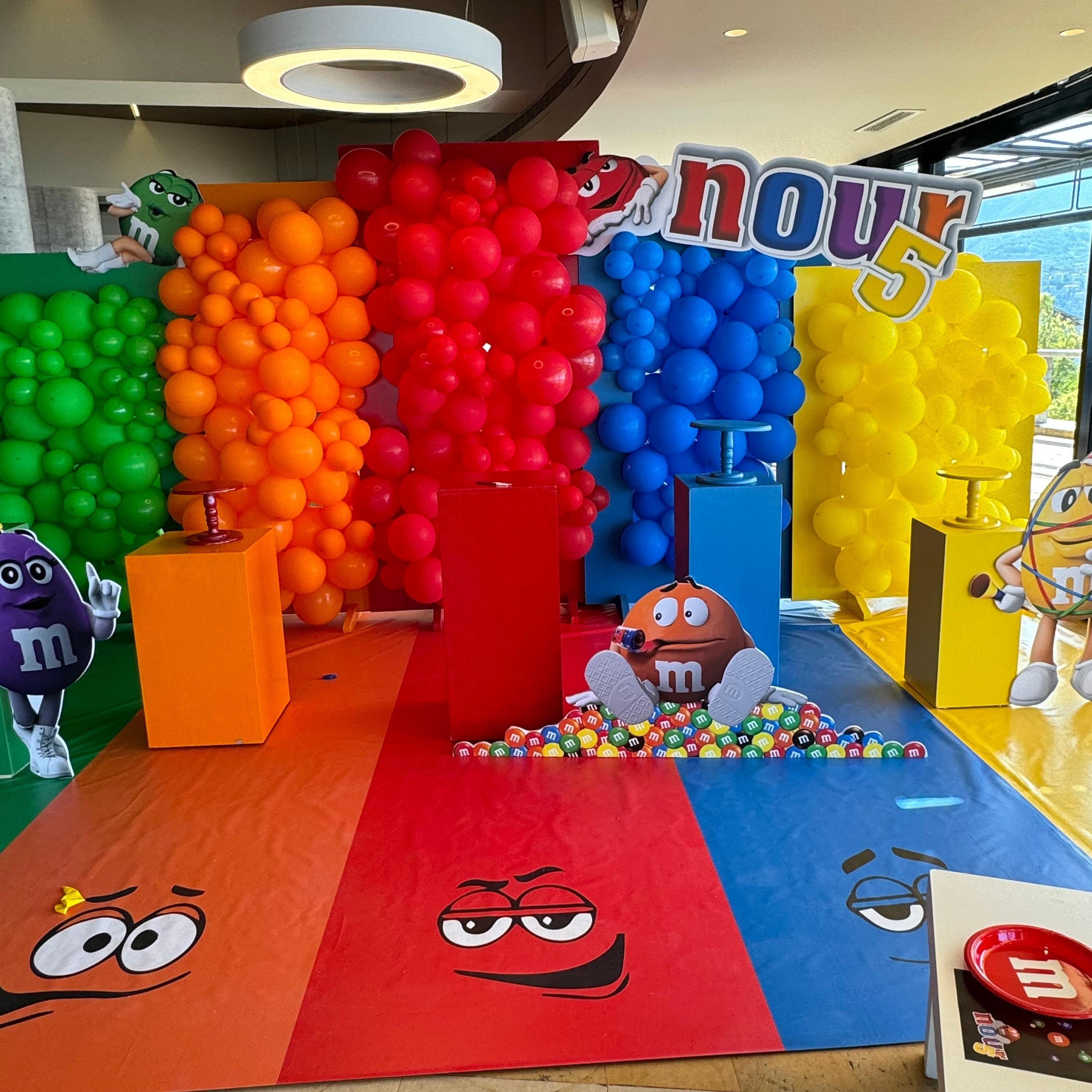 Colorful themed event setup with balloons and M&M-themed decor