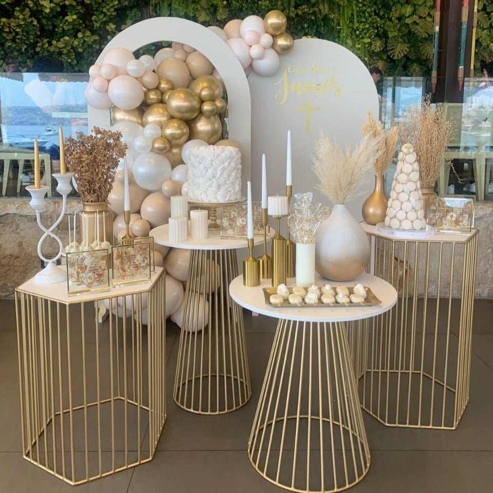 Decorative setup with gold and white balloons, candles, and table settings.