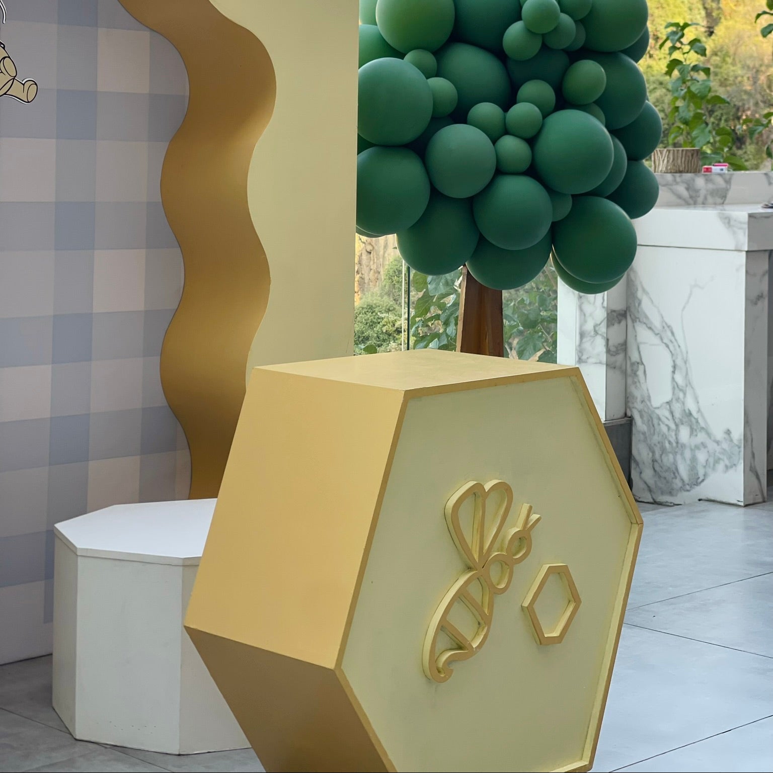 Decorative yellow and gold hexagonal structure with a green spherical plant in an outdoor setting.