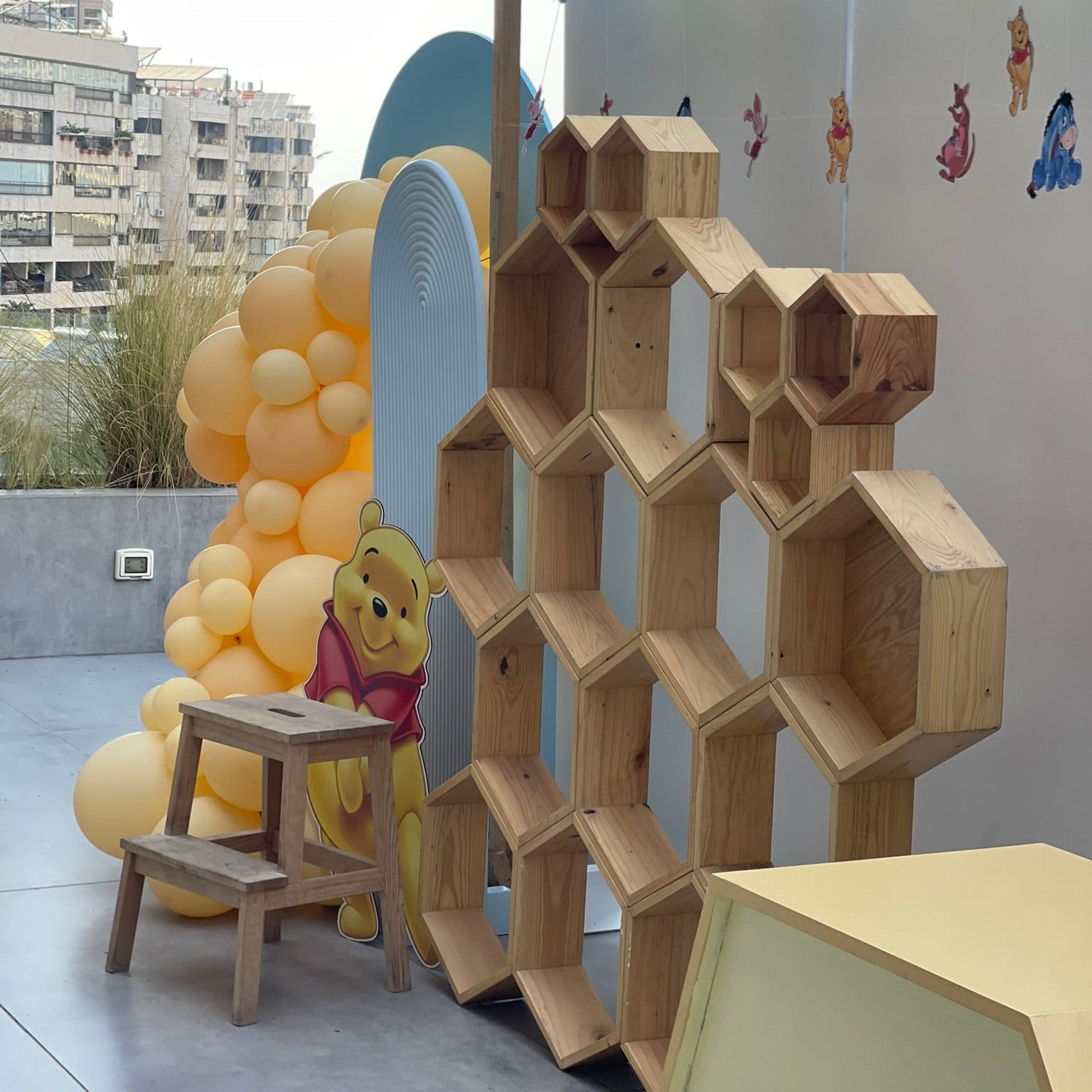 Children's play area with wooden honeycomb structure, Winnie the Pooh character, and balloons.