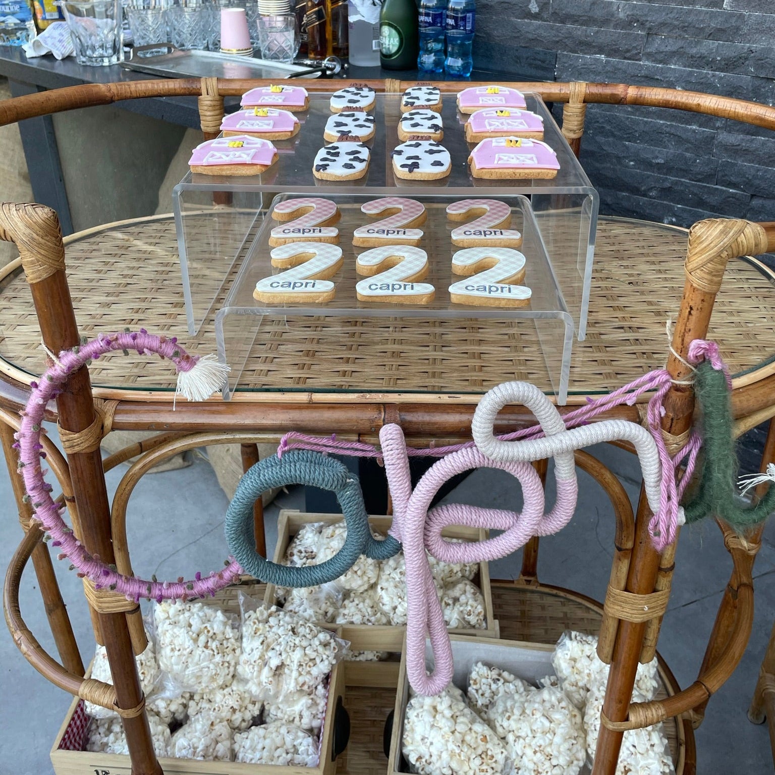 Decorative setup with cookies, bottles, and decorative items on a table against a stone wall.
