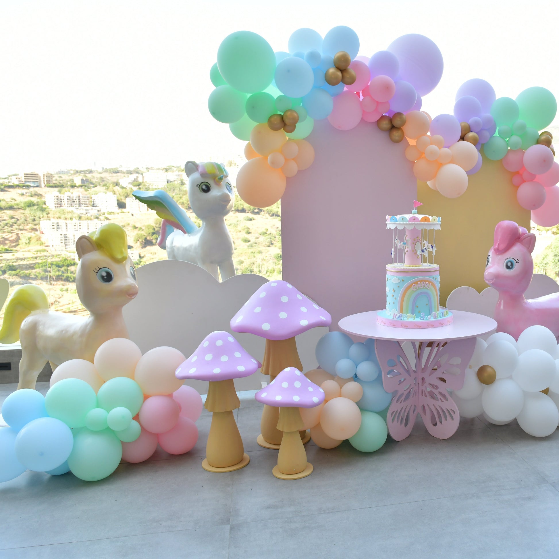 Children's birthday party setup with balloons, cake, and toys on a table.