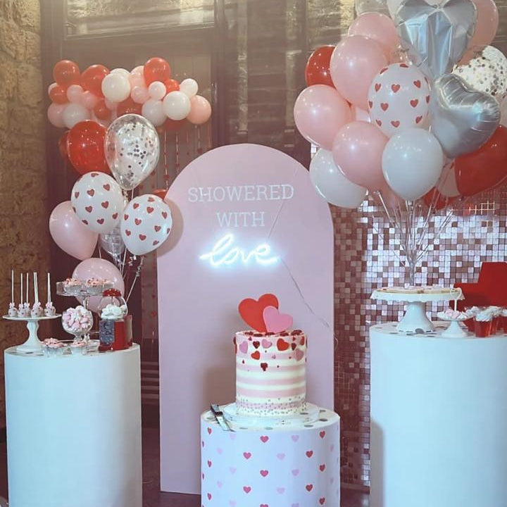 Decorative setup with balloons, cake, and festive lights on a stage.