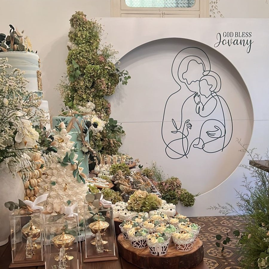 Decorative table setup with floral arrangements, cakes for a holy communion