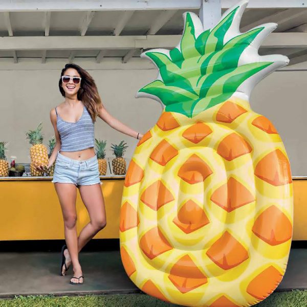 Woman standing next to a large inflatable pineapple pool float.