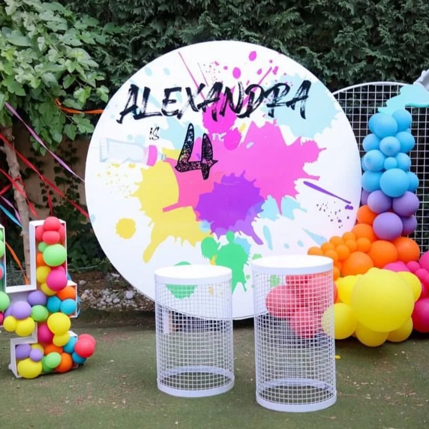 Colorful birthday party setup with a large round backdrop and tables