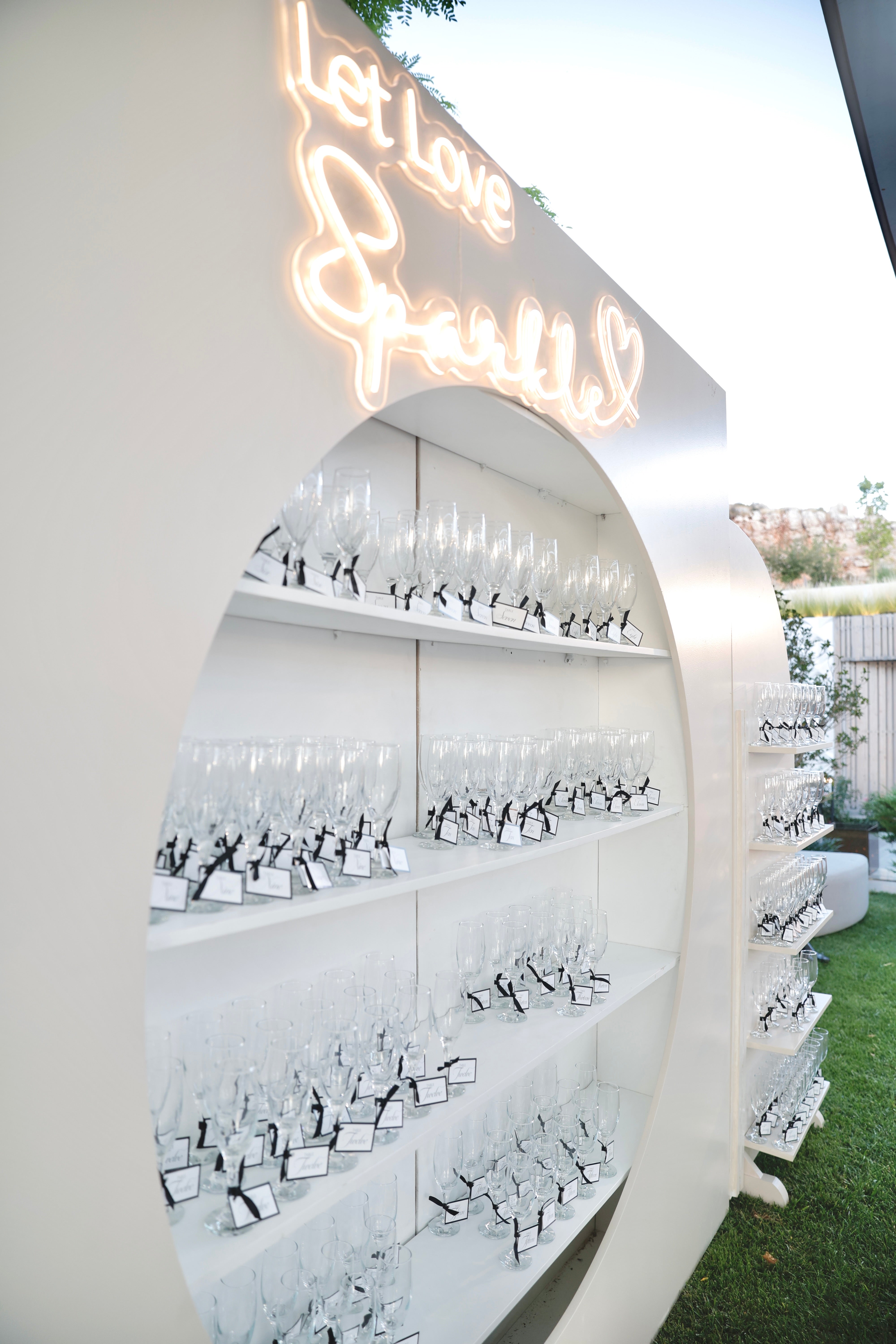 Decorative wall with wine glasses and a neon sign outdoors