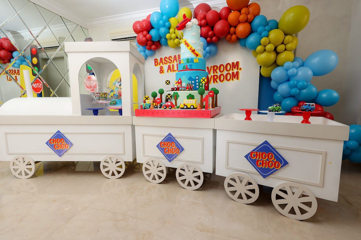 Decorative train with balloons and a cake on a table, likely for a children's party.