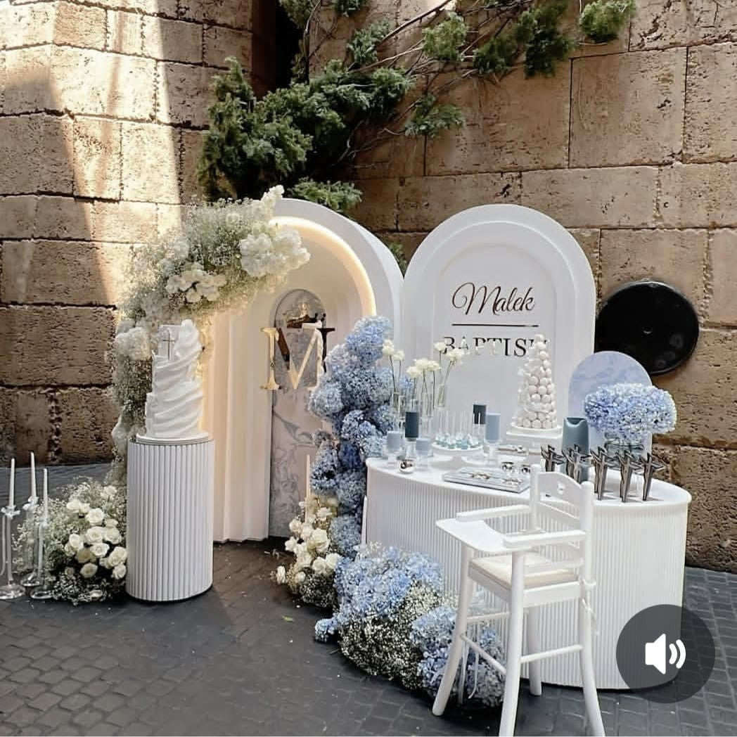 Decorative setup with floral arrangements and a kid's high white chair for a christening and baptism.