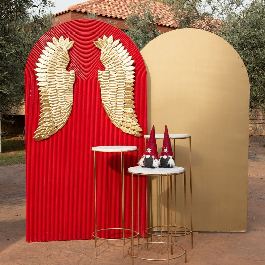 Decorative arches with gold wings on a red background, standing outdoors.