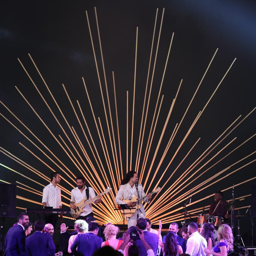 Band performing on stage with a starburst light design in the background