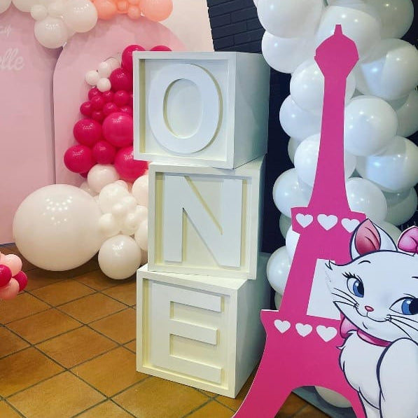 Decorative setup with 'ONE' blocks, Eiffel Tower, and balloons in a child's room.