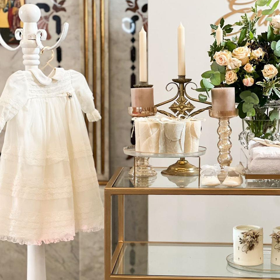 Mannequin wearing a white dress next to a decorative table with candles and flowers.