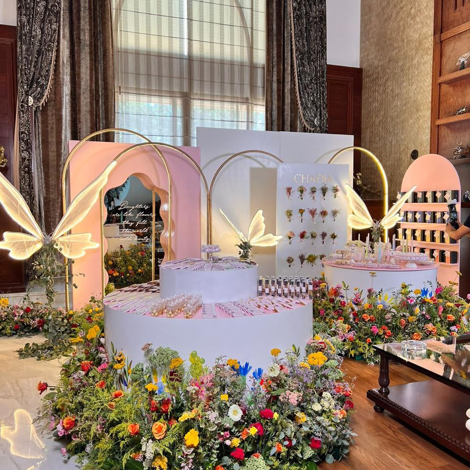 Decorative setup with flowers, cake, and chairs in a room with large windows.