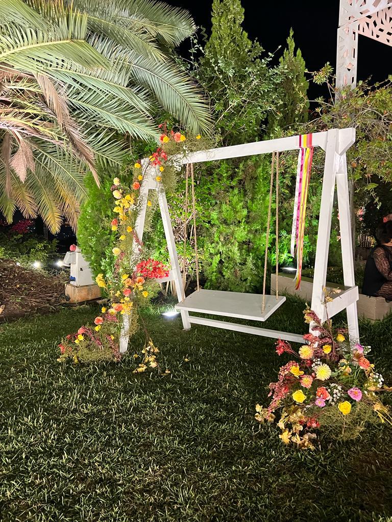 Decorative swing with flowers and ribbons in a garden setting at night.