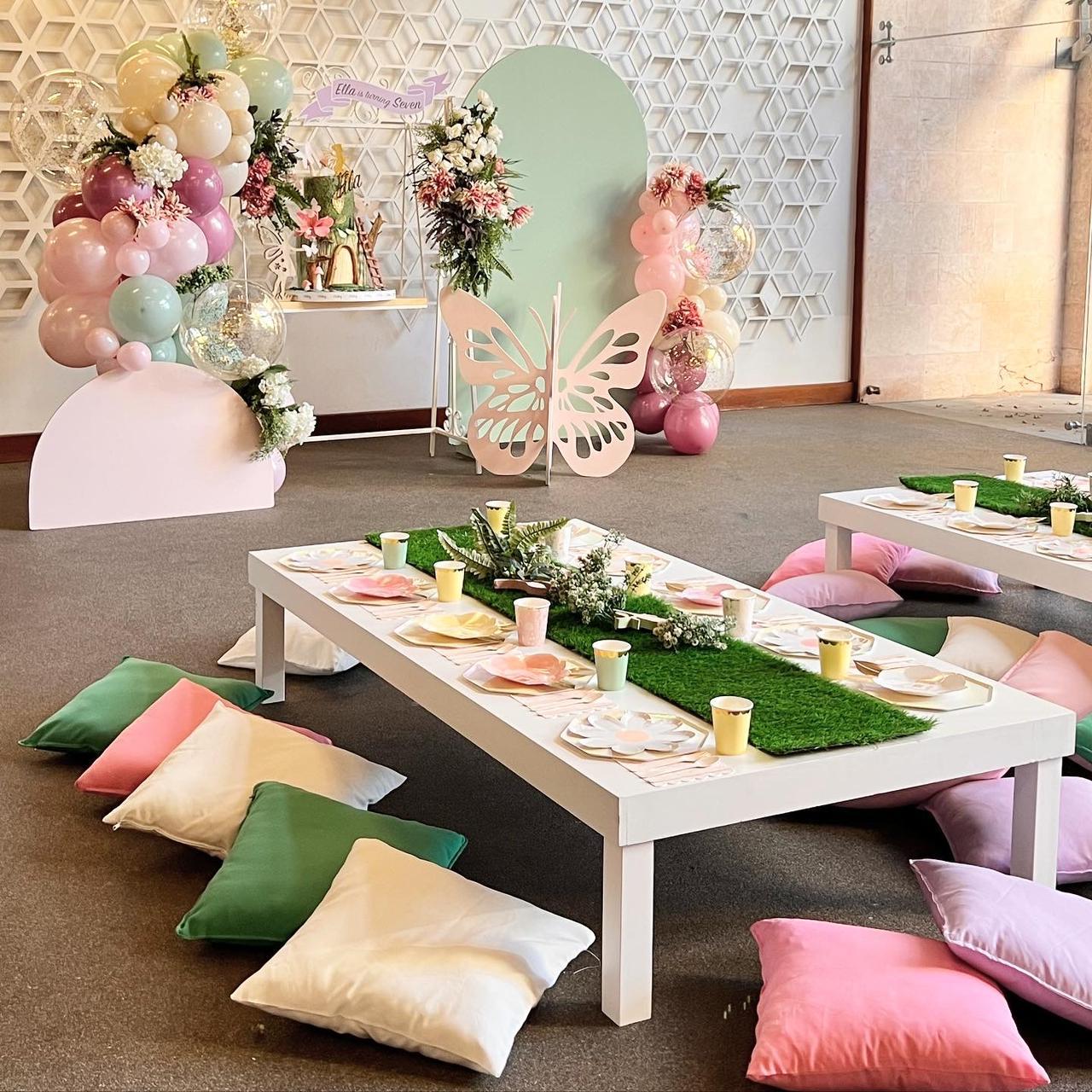 Decorated room with tables, balloons, and floral arrangements.