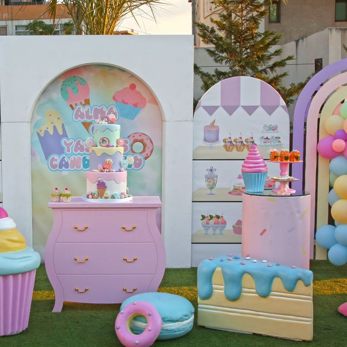 Pastel-colored inflatable decorations resembling ice cream cones, candy bars, and other sweets on a grassy outdoor setting.