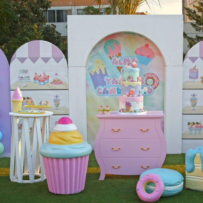 Pastel-colored inflatable decorations resembling ice cream cones, candy bars, and other sweets on a grassy outdoor setting.