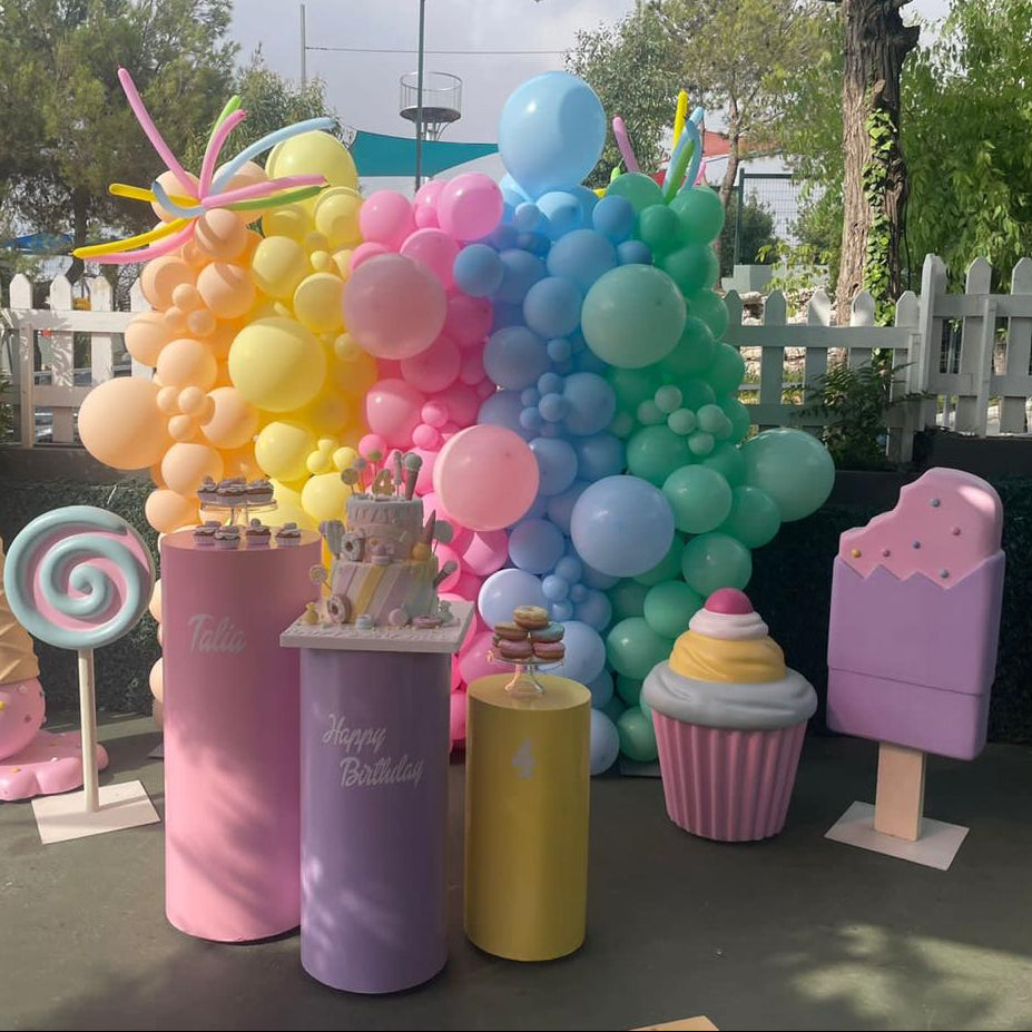 Colorful balloon arch with pastel-themed props on a outdoor setting