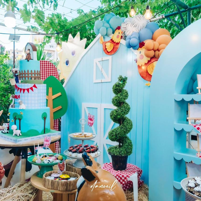 Colorful children's birthday with a blue barn, balloons, and various decorations.