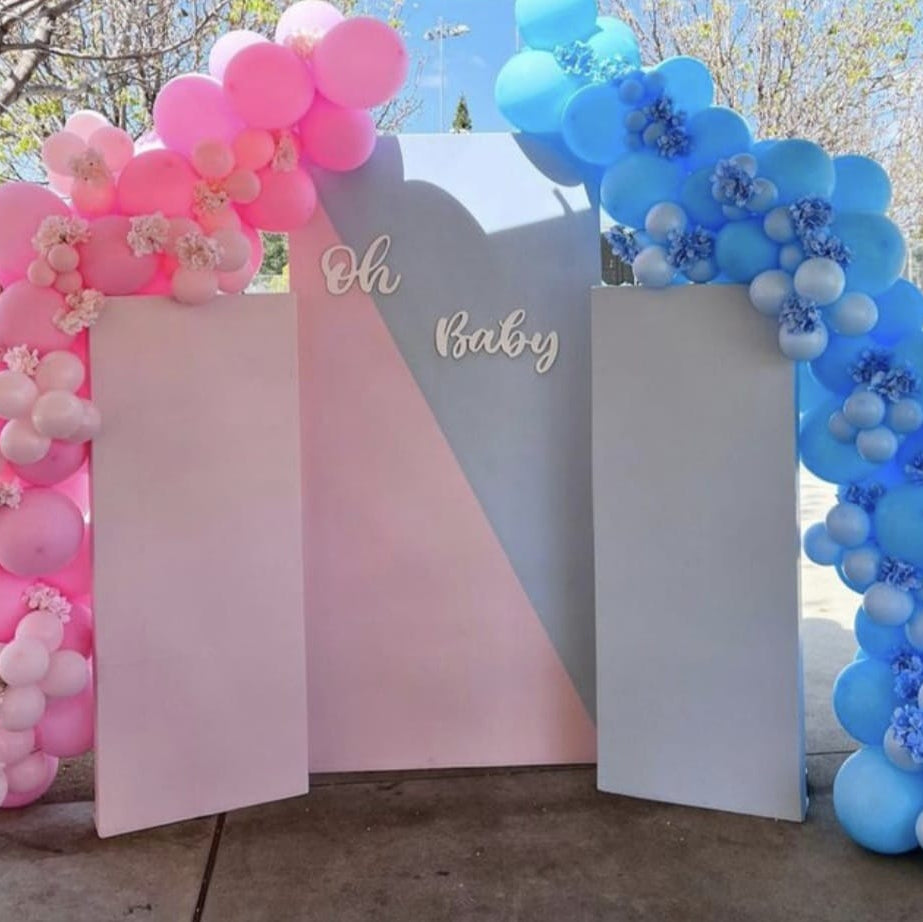 Decorative arches with pink and blue balloons and 'Oh Baby' sign outdoors.