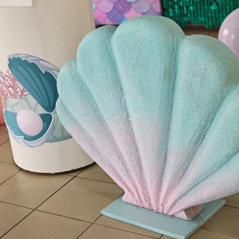 Large decorative shell with a gradient of blue to pink in a festive setting.