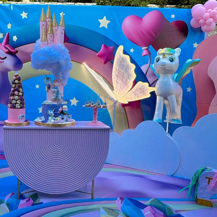 Colorful balloon arch with cartoon characters and decorations against a blue sky.