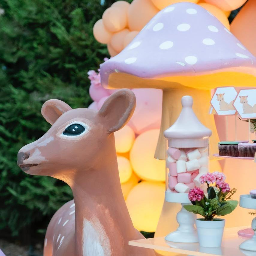 Decorative deer figure with a colorful background featuring balloons and a mushroom-shaped structure.