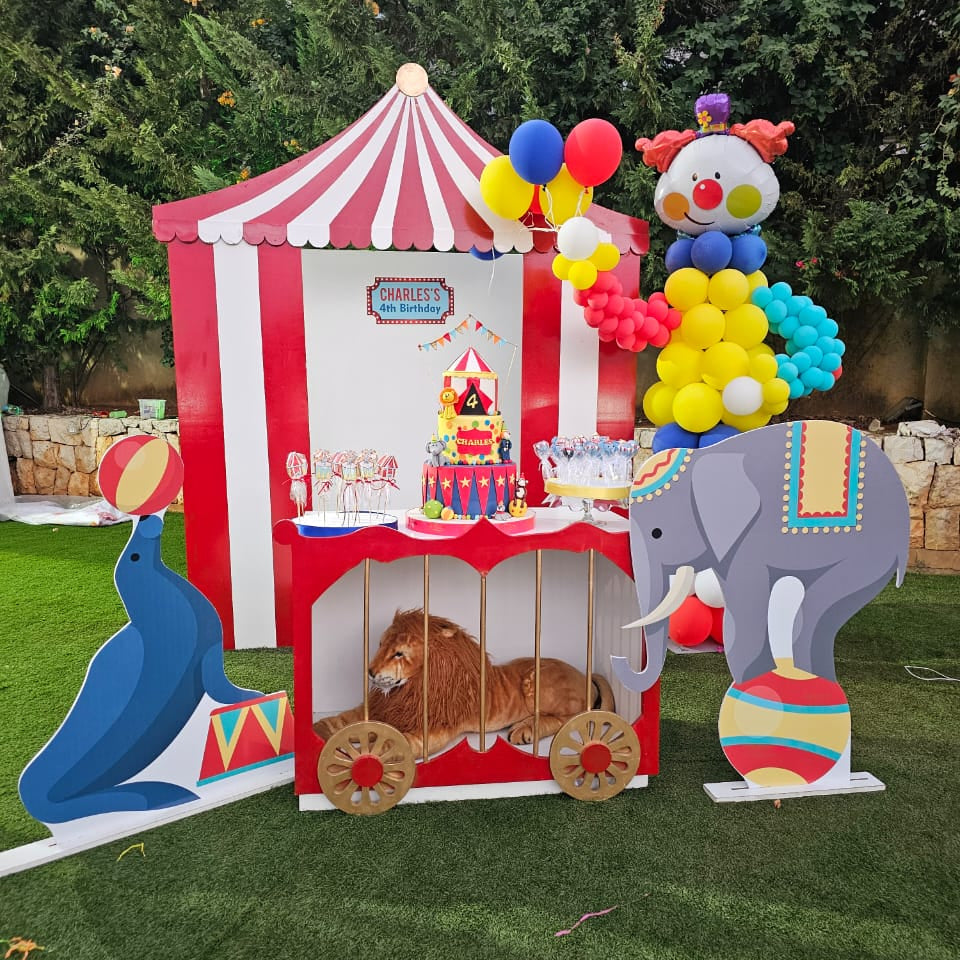 Circus-themed playhouse with balloons and animal cutouts on grass