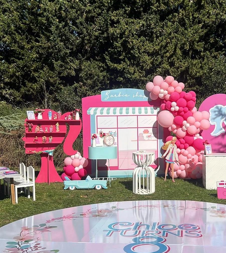 Barbie-themed birthday party setup with pink and blue decorations, balloons, and dolls.